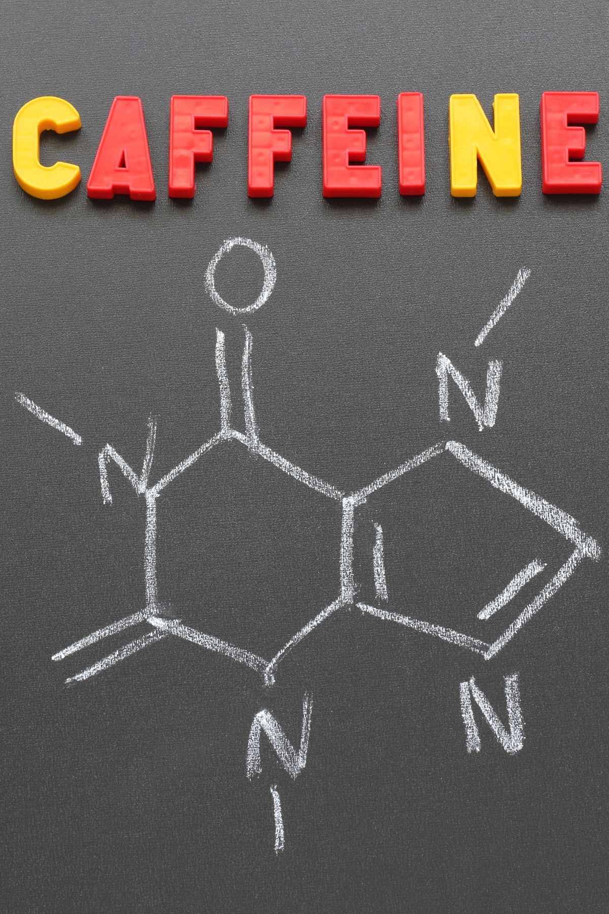 the compound structure of caffeine drawn on a chalk board.
