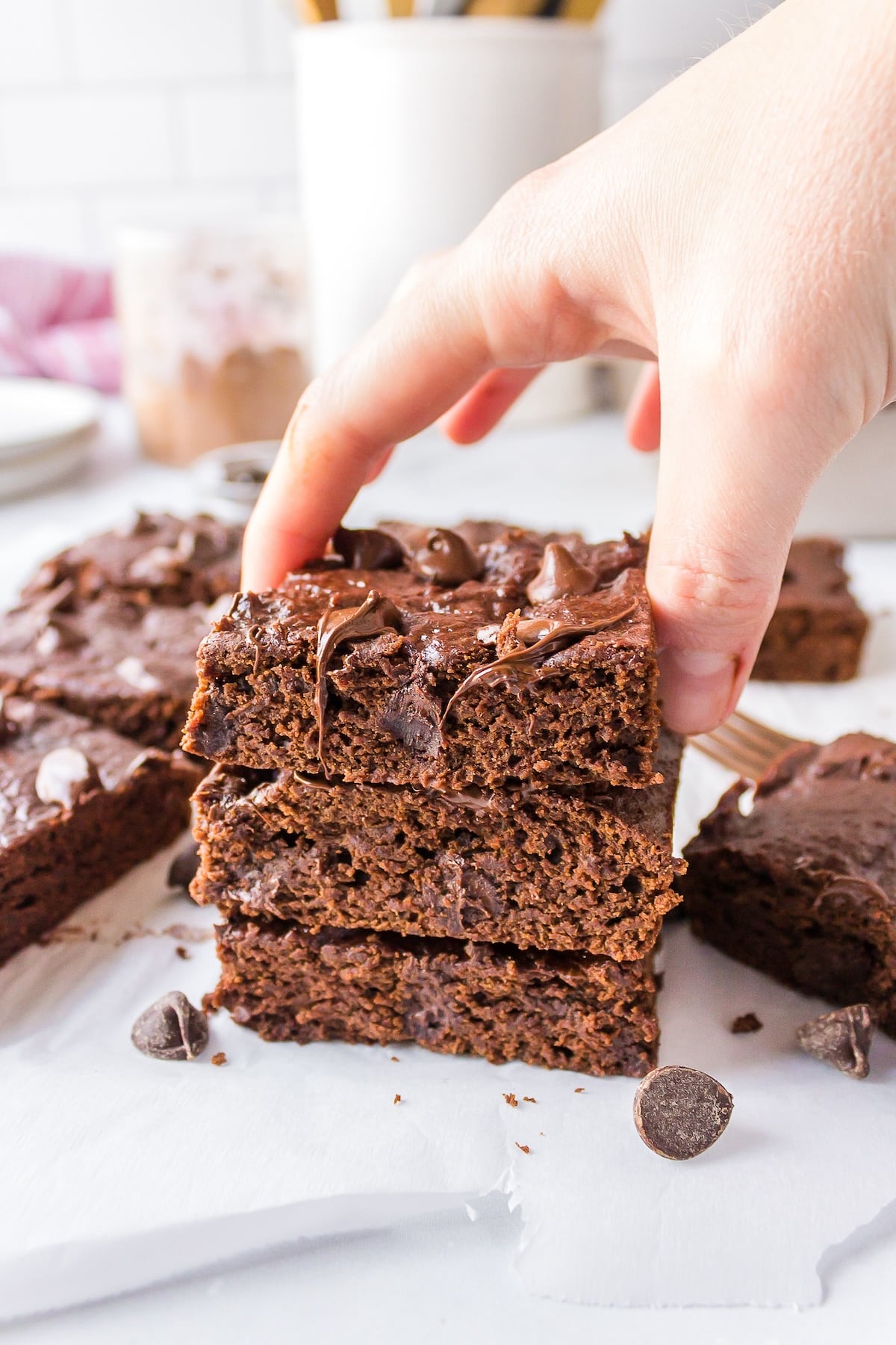 hand reaching for baked fudgy brownies on plate.