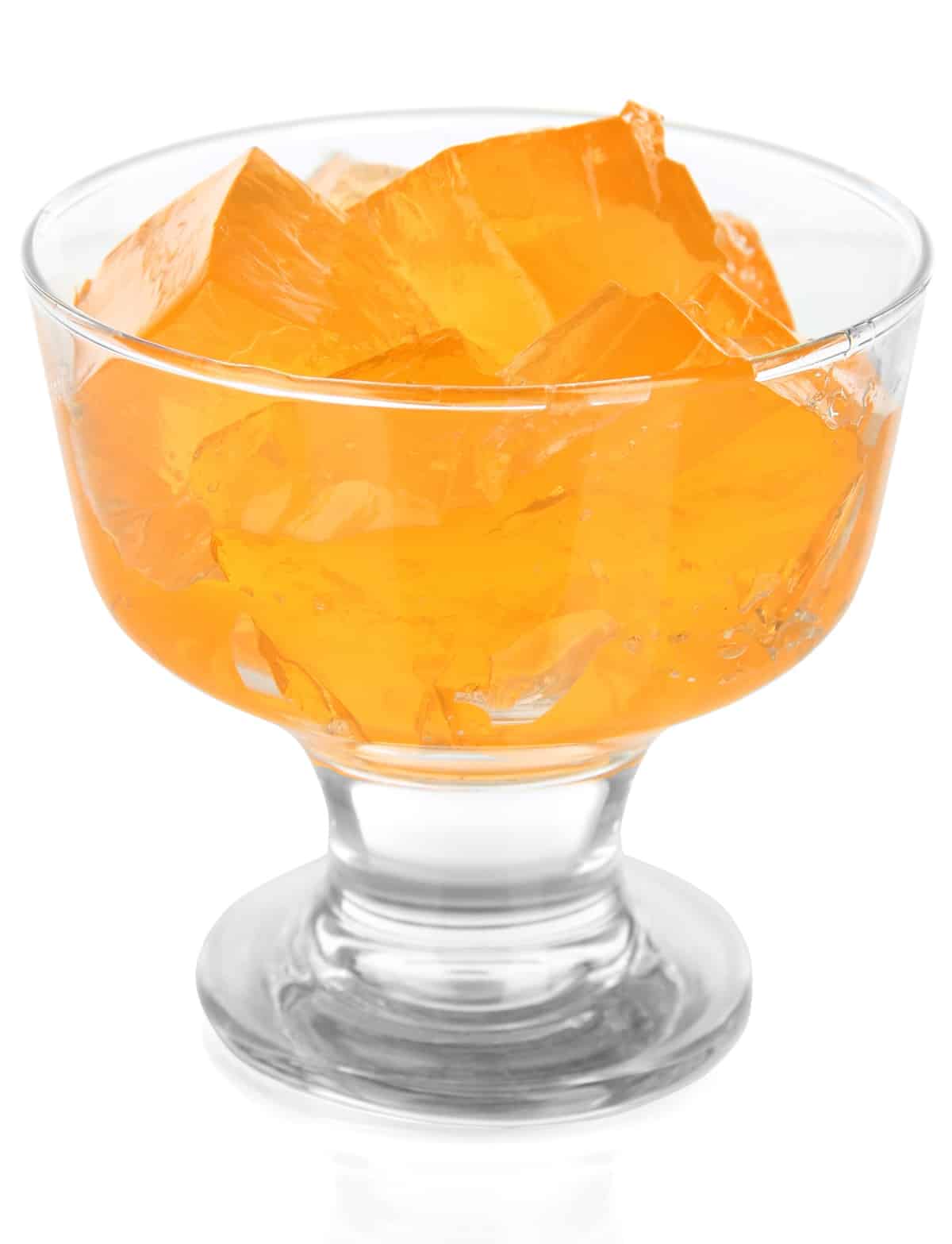 orange jello cut into cubes in a parfait glass.