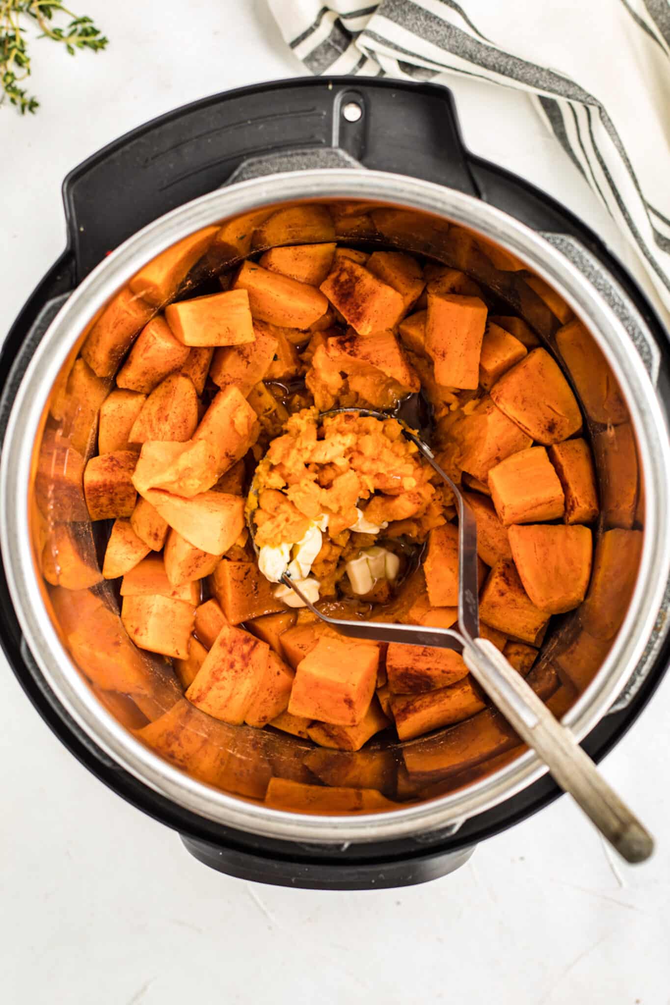 mashing the cooked sweet potatoes in the instant pot.