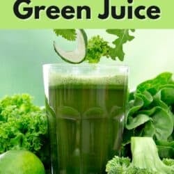 a glass of green juice surrounded by vegetables.