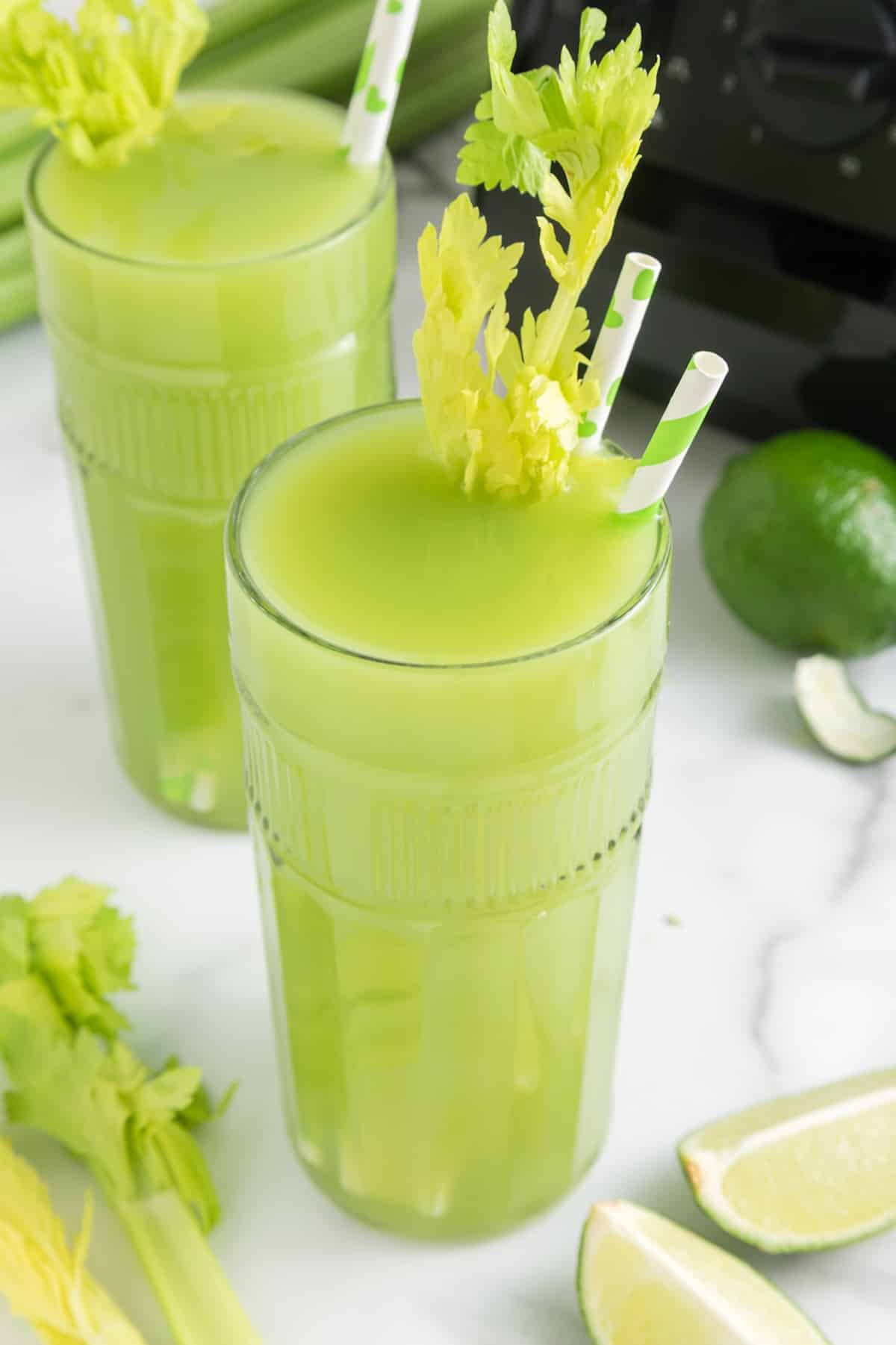 two glasses of celery juice with striped straws.