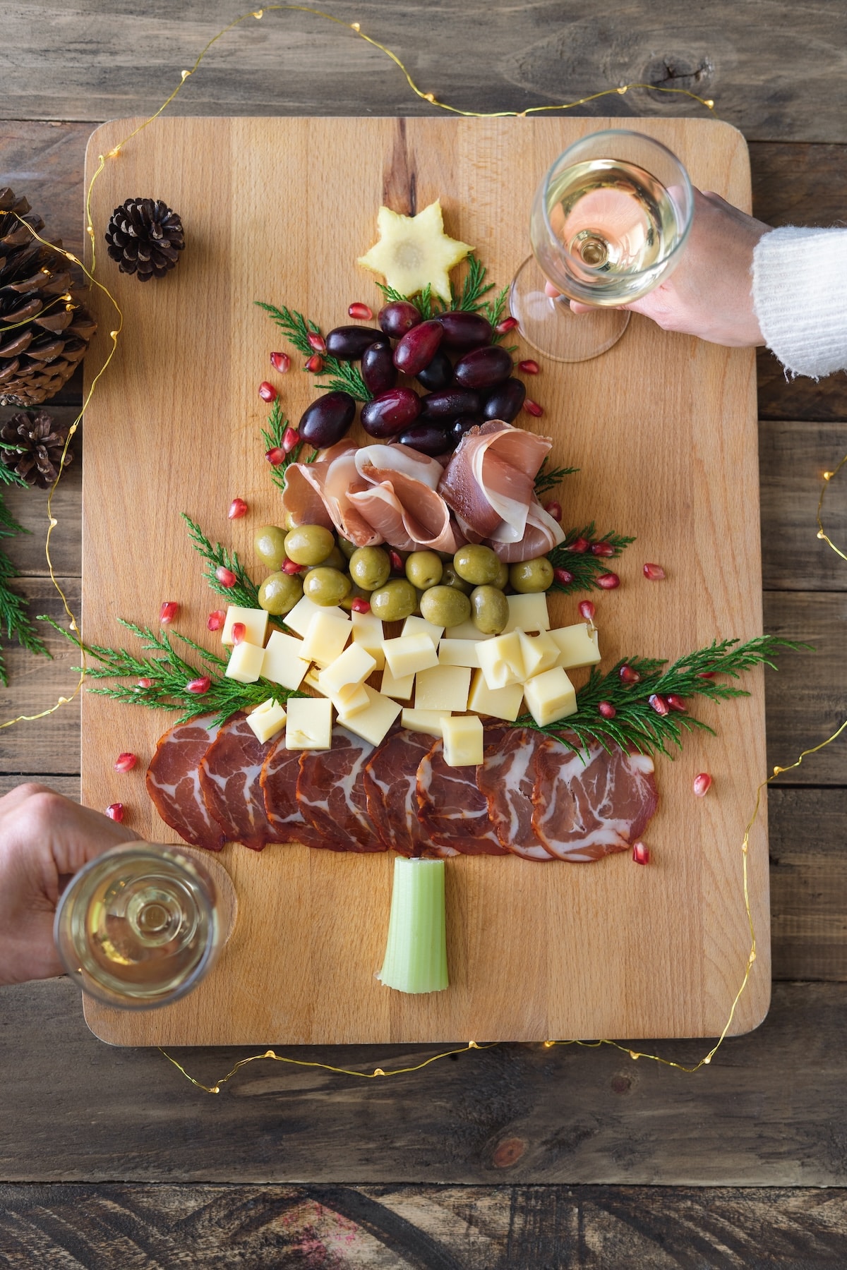 guests enjoying wine with christmas tree shaped charcuterie board. 