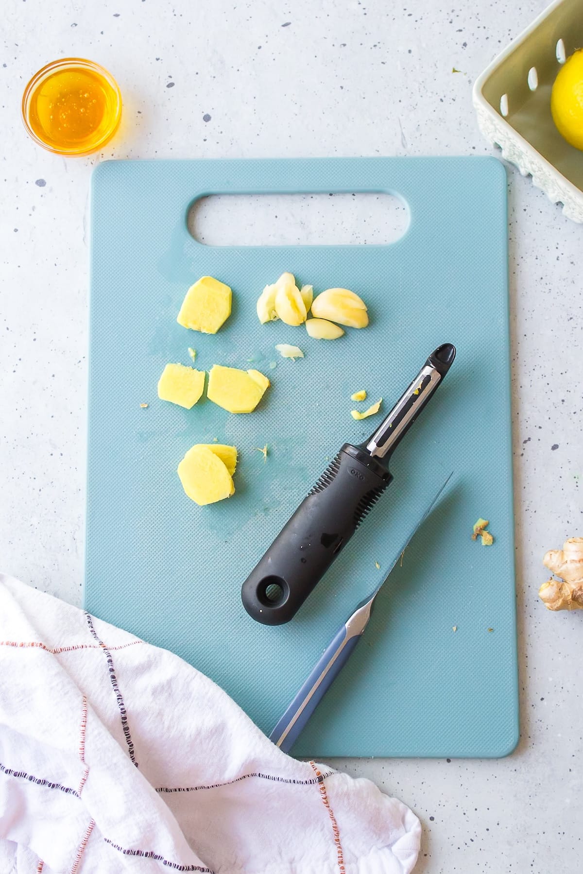 ginger and garlic being peeled and sliced on a cutting board.