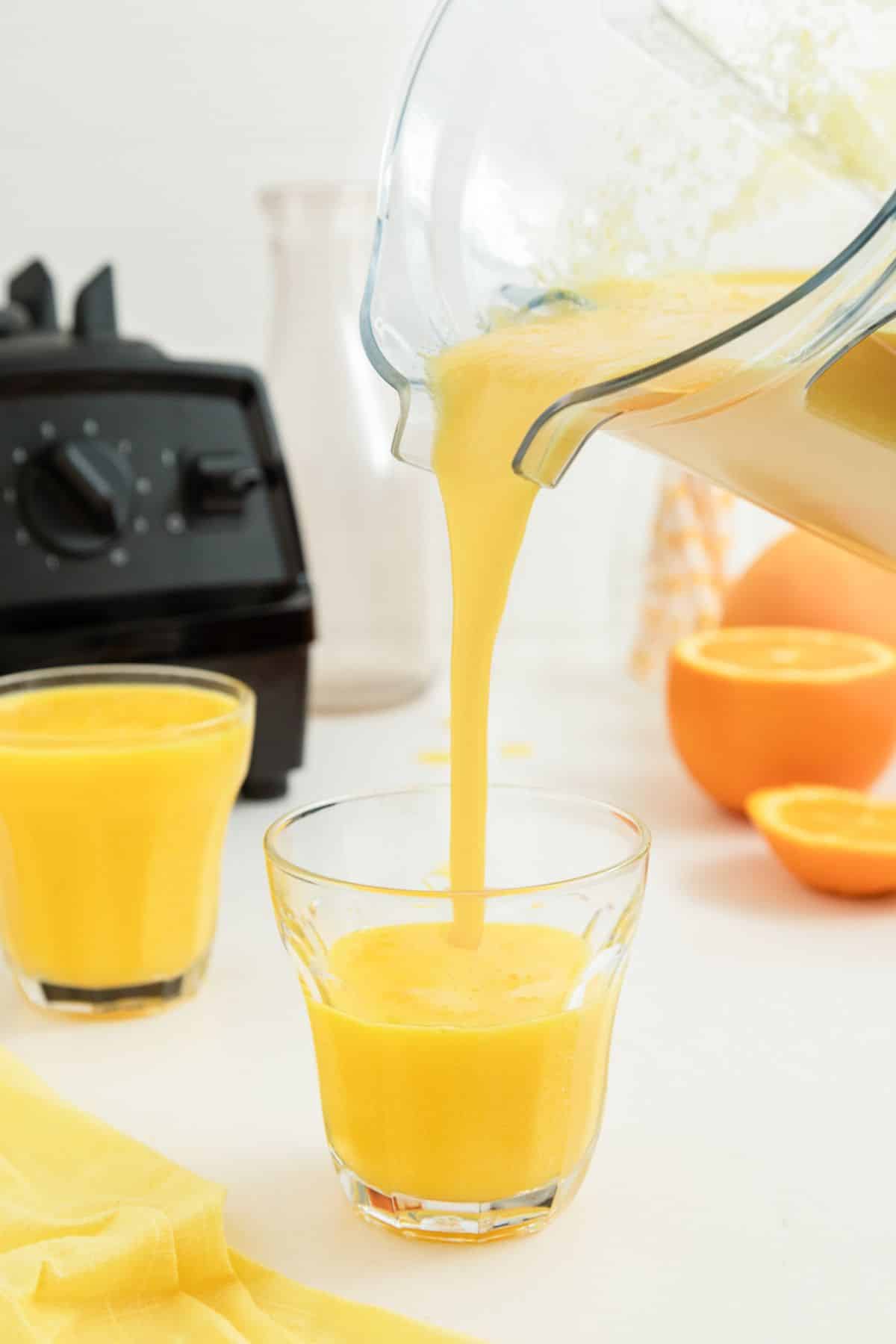pouring orange juice into a glass from a Vitamix blender. 