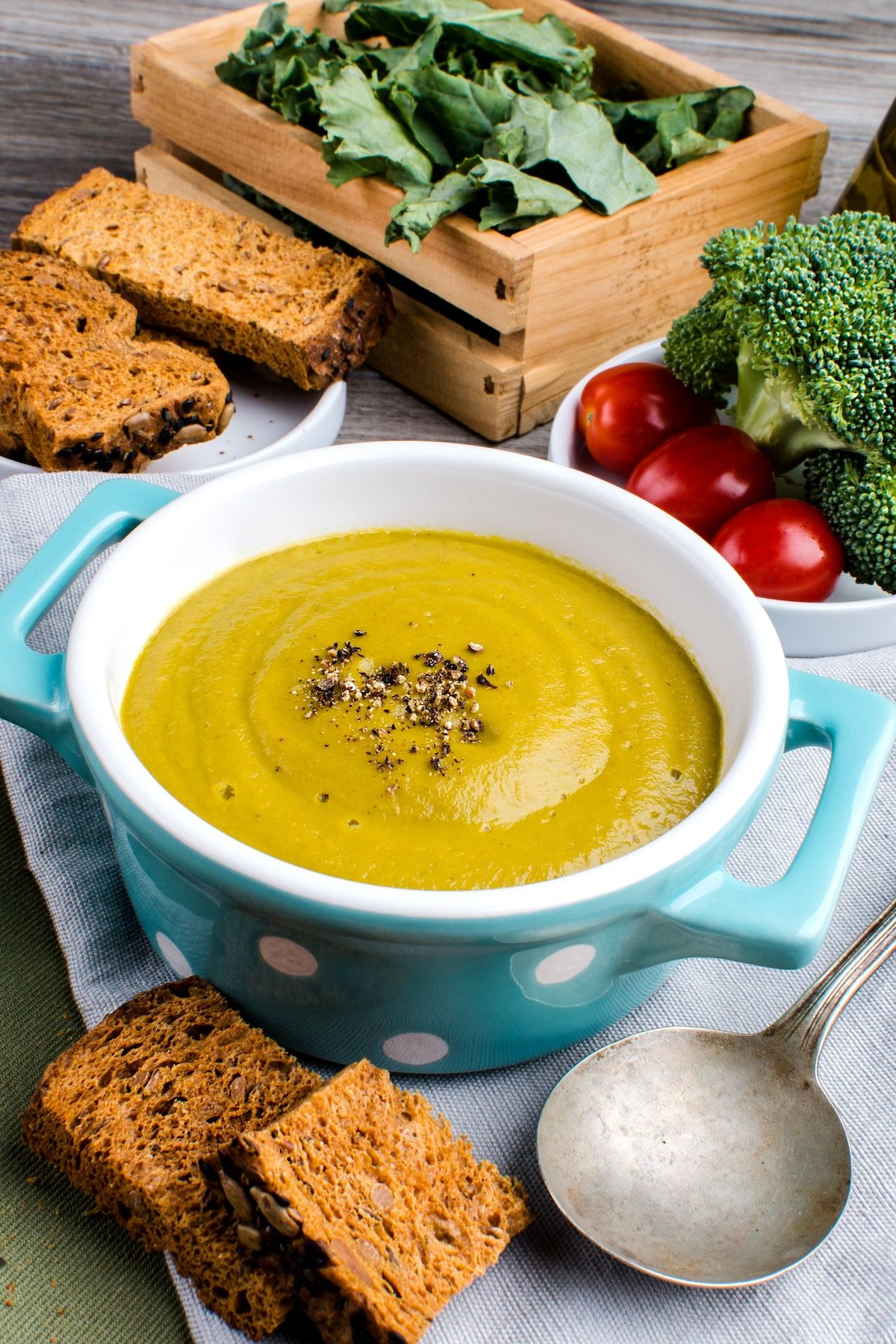 bowl of plant-based broccoli soup on table with toasted bread.