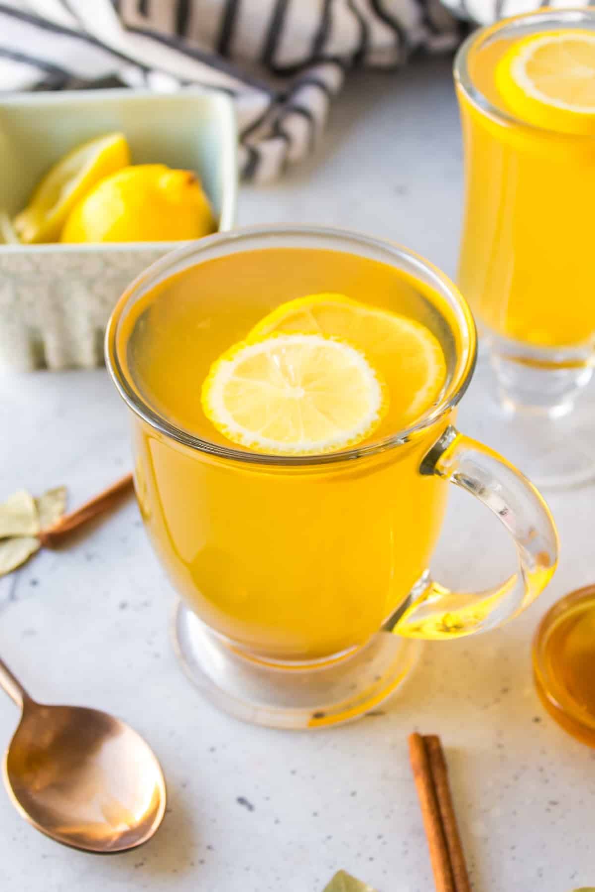 a glass of cinnamon and bay leaf tea with fresh lemon slice on top.