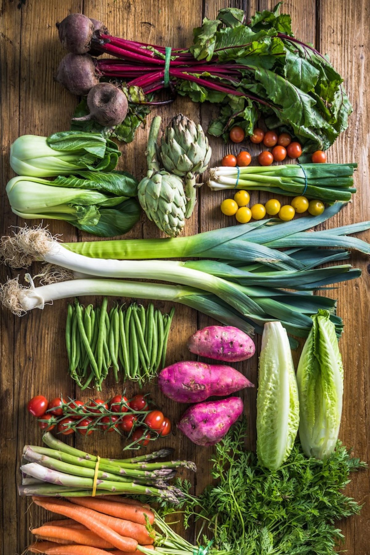 a variety of vegetables on a wooden table.