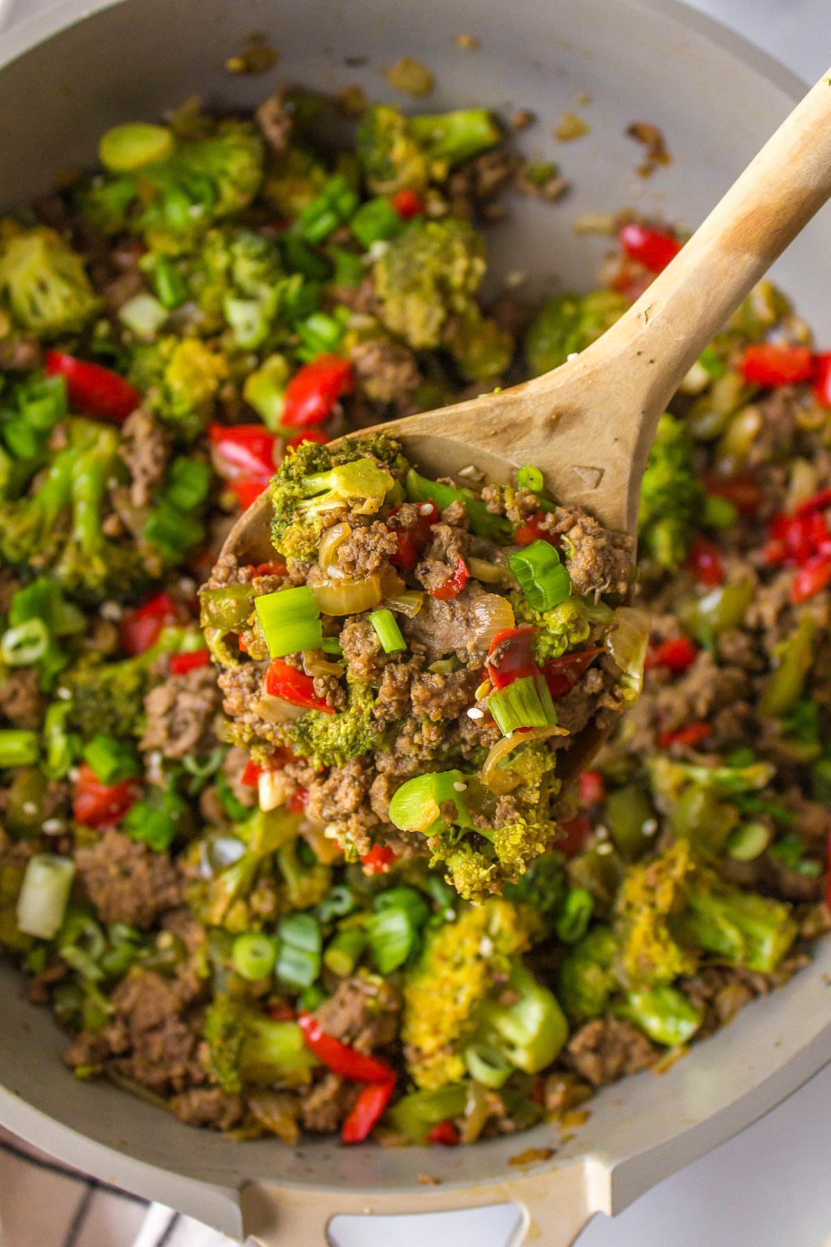 a wooden spoon stirring bison stir-fry in a pan.