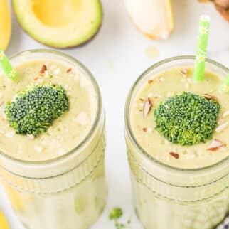 two glasses of smoothie with broccoli florets on top.