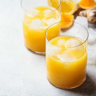 a glass of orange lemon ginger juice with ice.