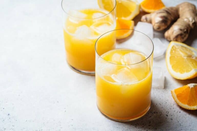 a glass of orange lemon ginger juice with ice.