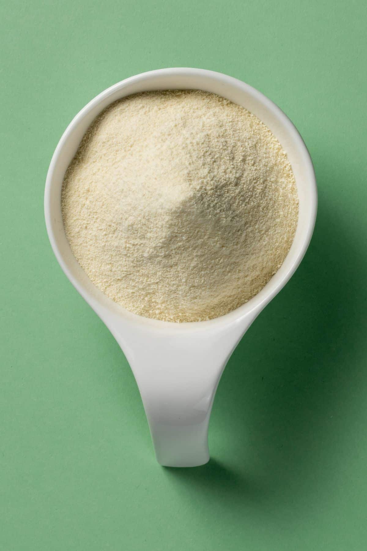 a white measuring cup of whey protein isolate.