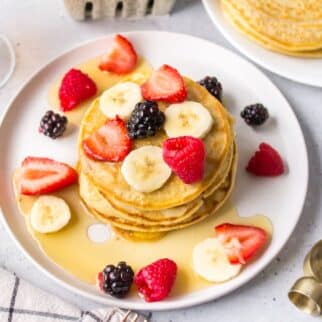 a plate of dairy-free pancakes topped with syrup and fruit.