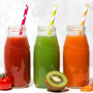 trio of colorful fruit juices in jars with straws.
