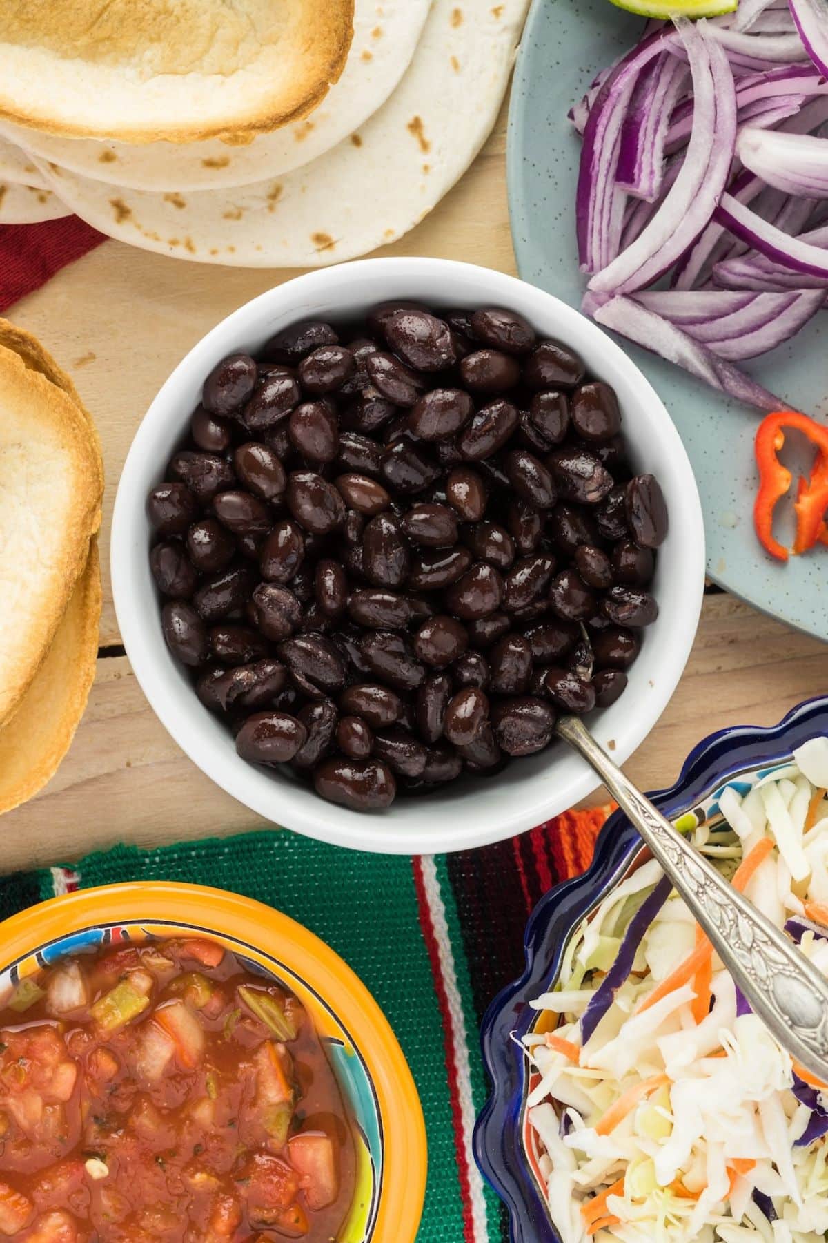 a bowl of black beans surrounded by other foods.