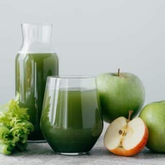green juice on table with fresh ingredients.