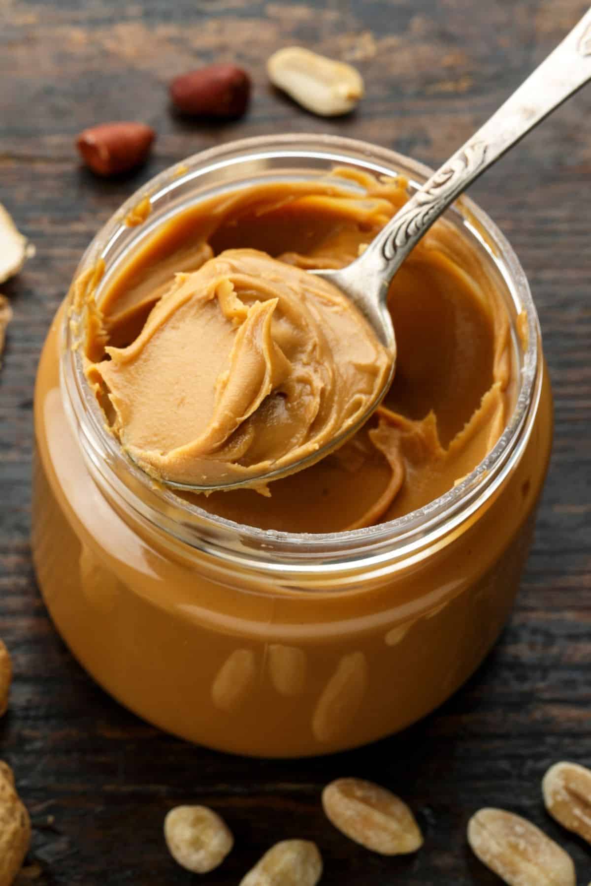 a spoon scooping a serving of peanut butter out of a jar.