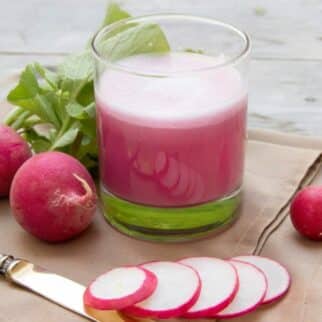 a glass of radish juice next to sliced radishes.