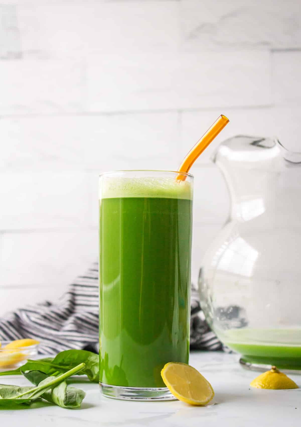 green spinach juice served in tall glass with straw.
