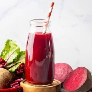 glass of fresh beet juice on table with fresh beets.