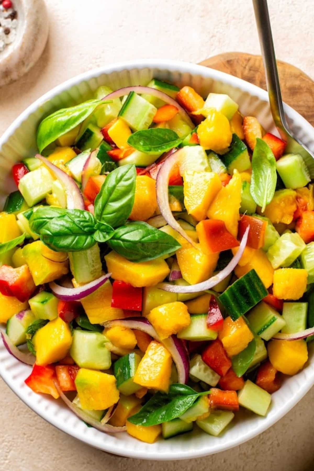 bowl of salad with cucumber mango and bell pepper.
