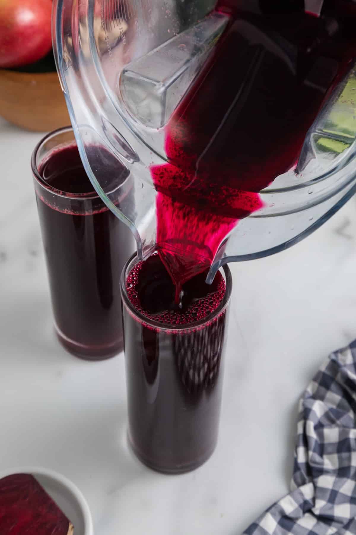 pouring fresh beet juice into glass.